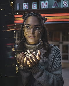 woman wearing gray sweater holding lighted brown string lights outdoors thumbnail