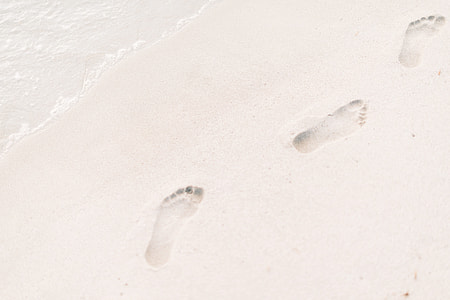 sea waves beside foot printed left on the sand thumbnail