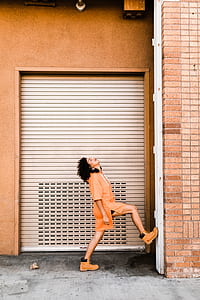 woman standing in front of roller shutter while raising her right foot thumbnail