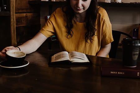 woman reading book while holding ceramic mug thumbnail