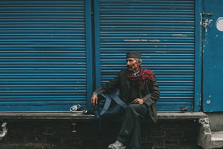man sitting on concrete bench in front of roller shutter door thumbnail