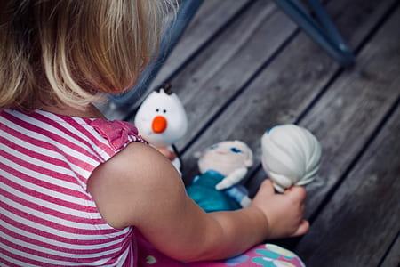girl holding Frozen Olaf and Elsa plush toy while playing thumbnail