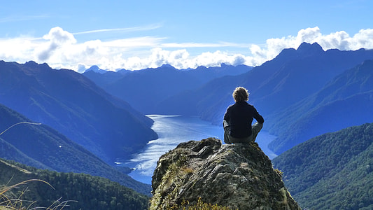 person sitting on top of a mountain during daytime thumbnail