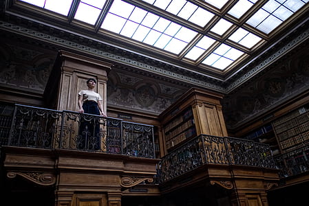 low-angle photography of woman standing on white metal railings inside brown building thumbnail