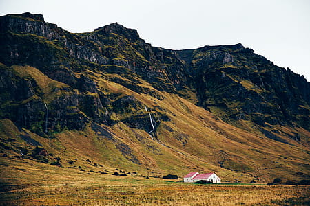 A farm home near rocky hills surrounded by meadows thumbnail