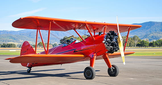 red plane on gray pavement at daytime thumbnail