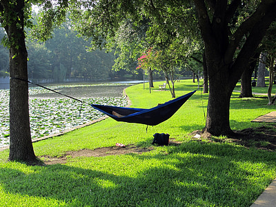 person lying on blue hammock surrounded by trees thumbnail