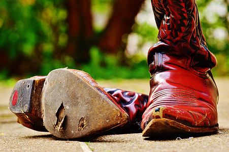 selective focus photo of pair of brown cowboy boots on brown concrete surface thumbnail