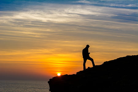 silhouette of a man walking uphill during sunset thumbnail