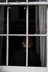 man in black collared top sitting beside white framed clear glass window during daytime thumbnail