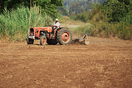 man riding red tractor on soil thumbnail