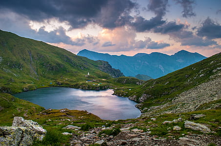 body of water between green and gray mountain during daytime thumbnail