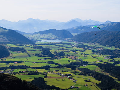 aerial view of green grass field near mountain under gray sky thumbnail