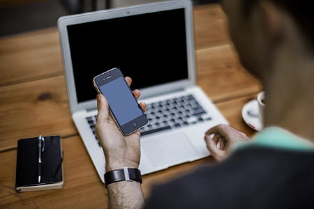 person holding turned off iPhone in front of turned off MacBook Air thumbnail