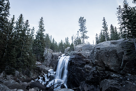 waterfalls surrounded with pine tree during daytime thumbnail