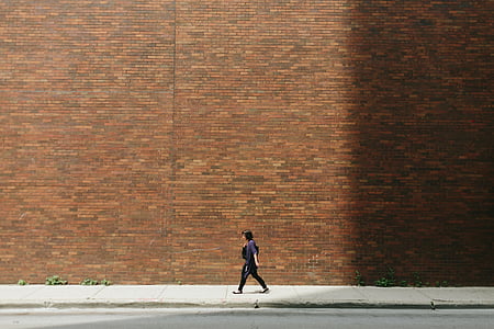 woman walking down the street along red brick wall thumbnail