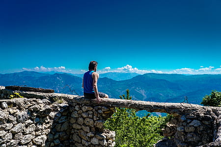 man wearing blue shirt sitting in front of mountains thumbnail