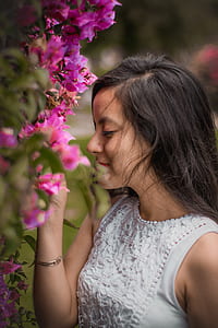 woman sniffing pink bougainvillea flowers selective focus photography thumbnail