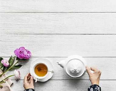 top view photography of person pouring tea while using teapot on teacup thumbnail