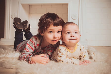 baby on white fleece textile beside a boy wearing grey sweater thumbnail