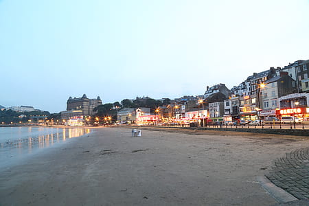 three people standing on gray sand near buildings on road thumbnail