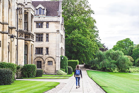 girl walking beside green grass field during daytime thumbnail