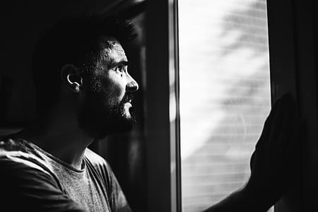 Greyscale Photo of Man Looking Through Window thumbnail