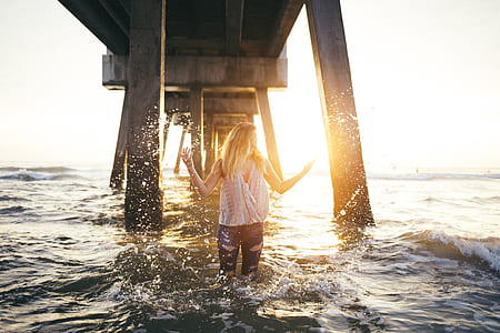 woman standing in the body of water under dock thumbnail