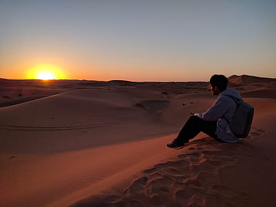 man with backpack sitting on sand dune thumbnail