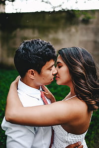 man in white dress shirt kissing woman in white spaghetti strap dress thumbnail