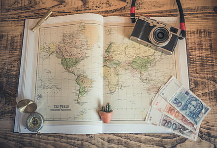black SLR camera placed on The World map atlas thumbnail