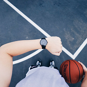 person wearing black analog watch and holding spalding basketball thumbnail