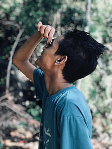 tilt-shift lens photo of man holding his nose whilst standing thumbnail