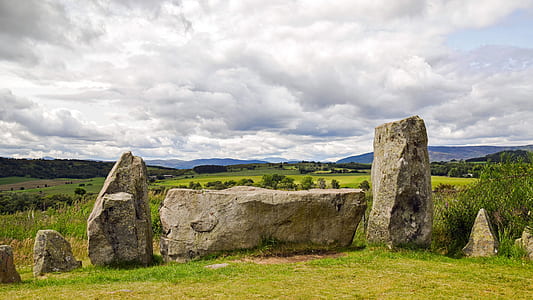 brown rock formation surrounded green grass field thumbnail