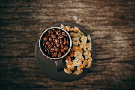 cup filled with coffee beans beside flowers thumbnail