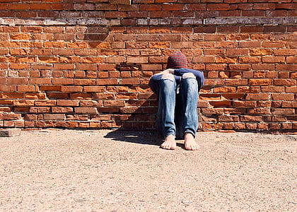 person sitting and leaning on brown concrete wall at daytime thumbnail