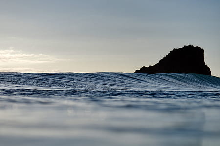 body of water near rock at daytime thumbnail