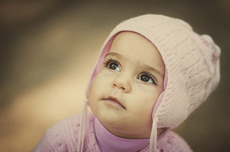 selective focus photography of baby wearing pink knit hat thumbnail