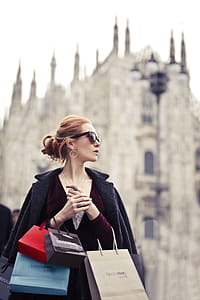 A young blond woman wearing a satin dress holding shopping bags in her hands thumbnail