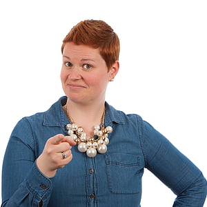smiling woman wearing gold-colored white pearl bubble necklace and blue chambray long-sleeved shirt pointing finger thumbnail