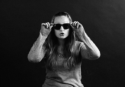 grayscale photography of woman holding sunglasses thumbnail