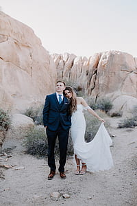 bride and groom standing in front of brown rock during daytime thumbnail