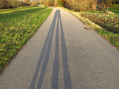 two person's shadow on street between green grass thumbnail