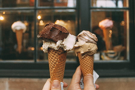 persons holding two chocolate ice creams thumbnail
