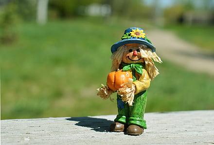 selective focus photography of scarecrow holding pumpkin figurine thumbnail