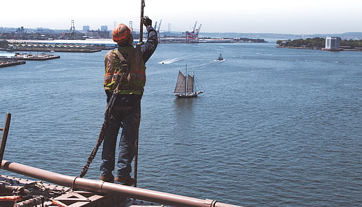 man wearing hard hat on building near body of water thumbnail