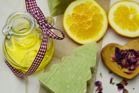 close-up photography of clear bottle with yellow liquid beside Christmas tree accent decor on table thumbnail