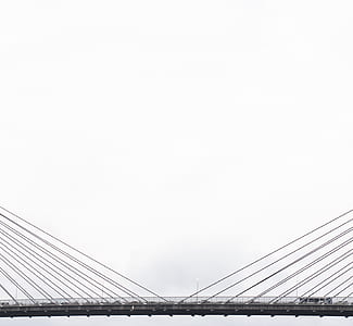 assorted vehicle passing on gray metal suspension bridge during daytime thumbnail
