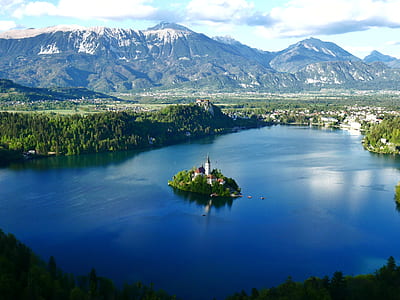 aerial view of island with castle surrounded by mountains and body of water during daytime thumbnail