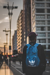 man with backpack standing on pathway surrounded with different vehicles and people thumbnail
